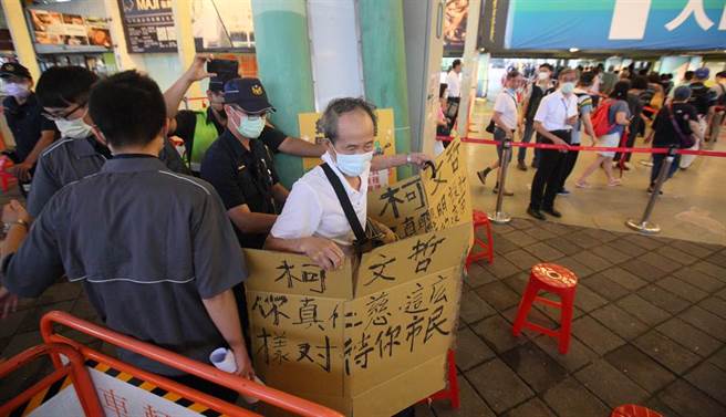 台北市13日起开放花博接种站为长者施莫德纳以及AZ两种疫苗。不过一早就有许多长者提前来排队，加上现场规划的动线相当混乱，现场骂声连连，并有一位民眾手持自制标语，痛批市长柯文哲无能，最后被辖区警方劝离。（张铠乙摄）