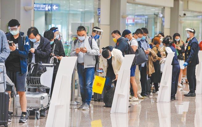 中央流行疫情指挥中心12日公布国内新增4例COVID-19确定病例，均为境外移入，为2例男性、2例女性，分别自保加利亚、马来西亚及美国入境。图为桃园机场入境旅客在下机后排队以手机填写入境健康声明书，并让CDC协勤人员核实，准备入境申报。（非新闻当事人）（陈麒全摄）