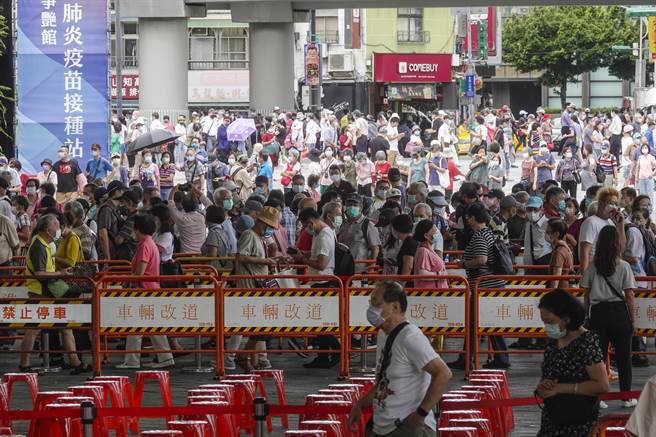 台北市花博公园大型接种站14日仍涌入大批民眾，排队长龙蜿蜒约1公里，昨日因现场混乱引发民怨，市政府今天派出大批工作人员疏导，秩序大致良好。（黄子明摄） 