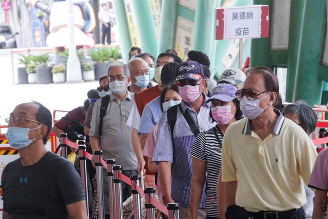 台北市花博公园大型接种站14日仍涌入大批民眾，接种站同时施打莫德纳、AZ两种疫苗，工作人员举着牌子引导民眾接种各自预定疫苗。（黄子明摄）