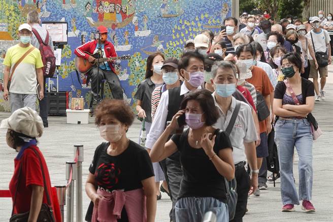 一名街头艺人在队伍旁自弹自唱，让市民边排队边听音乐，消解等待过程的枯燥无聊。（黄子明摄）