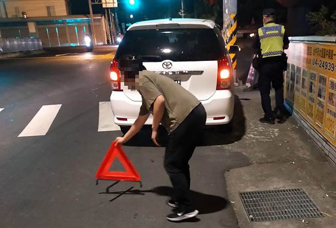 中市警局霧峰分局萬豐派出所員警，幫忙將故障在路中央的車推往路旁，並請駕駛確實擺放警告標誌，避免意外。（霧峰分局提供／黃國峰台中傳真）