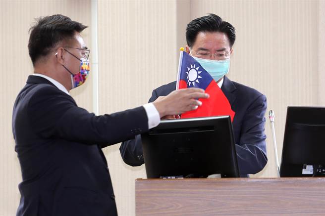 国民党立委江启臣（左）18日质询前，特别准备一面国旗送给外交部长吴钊燮（右），质问吴心中是否有国旗，并要求他现场挥舞。吴钊燮则回应自己心中当然有国旗，国庆等重要场合都有挥舞。（黄世麒摄）
