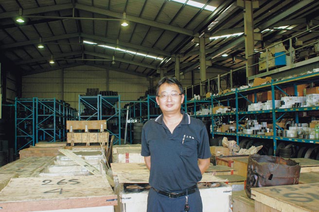 黑上传动总经理龚祖望，其周边为堆满皮带轮的公司仓储。图／黑上提供