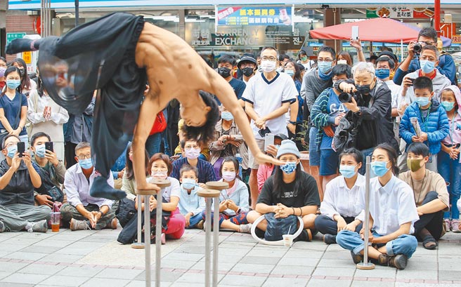 国内疫情趋缓，中央疫情指挥中心宣布19日起，将放宽民眾于室外从事运动，于室内外拍摄个人或团体照时，保持社交距离，可免戴口罩。17日适逢假日，民眾逛街戴着口罩，欣赏街头艺人表演。(陈俊吉摄)