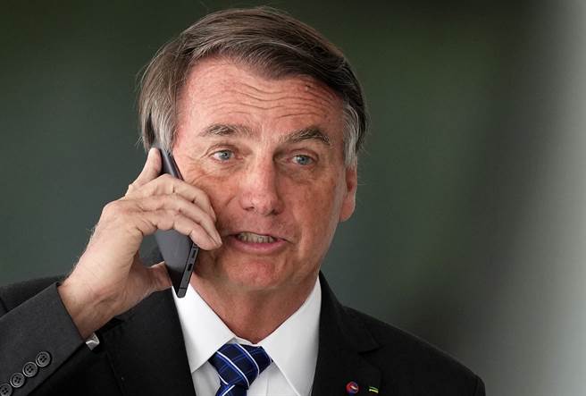 巴西總統波索納洛（Jair Bolsonaro）10月19日在巴西利亞總統府打手機的神情。（美聯社）