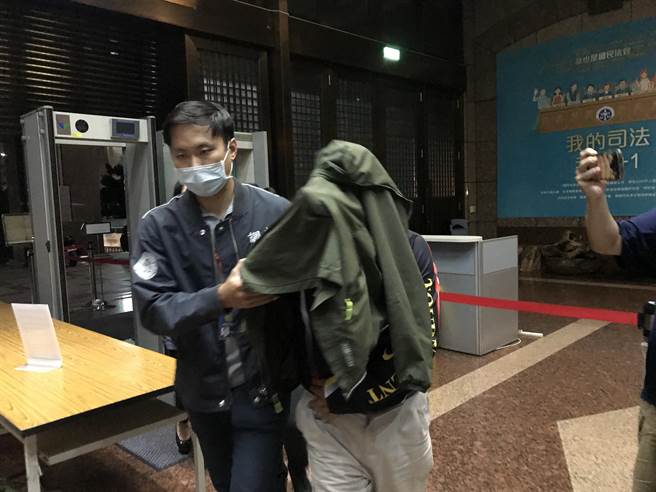 基隆市前议员韩良圻涉贪，步入地检署时以外套遮盖头部，基隆地院于21日凌晨裁定羁押禁见。（陈彩玲摄）