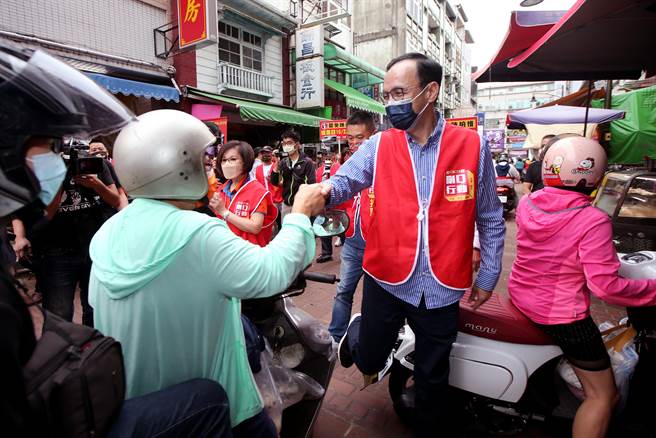 國民黨主席朱立倫，22日上午到霧峰市場，與刪Q團體一起拜託大家明天投下同意罷免票，經過一處機車障礙時，一腳跨了過去，還不忘伸手拜託。（黃國峰攝）
