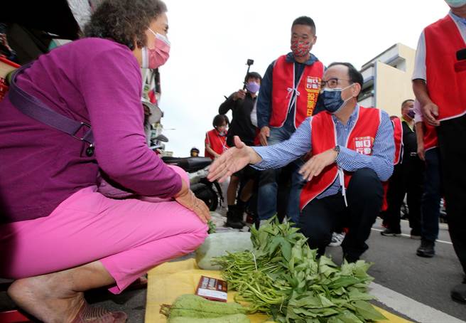 國民黨主席朱立倫，22日上午到霧峰市場，與刪Q團體一起掃街，拜託大家明天投下同意罷免票，蹲下來與一位攤商握手。（黃國峰攝）