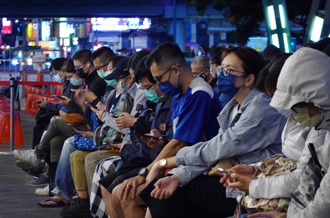 北市加大接種疫苗能量，夜幕低垂時分，大批等候民眾陸續進場。（姚志平攝）