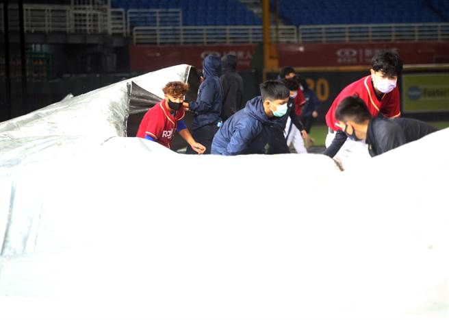 中华职棒乐天桃猿23日出战统一狮，6局下由于雨势过大，主审裁定比赛结束，工作人员连忙在球场内铺上防水布。（范扬光摄）