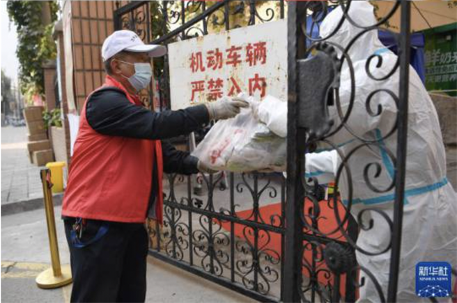 工作人員在蘭州市一封控管理的社區遞交住戶採購的生活物資。（新華社）