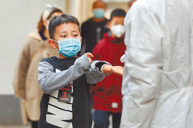 在大陸甘肅蘭州市的一所小學設立了臨時核酸檢測站，正在為學生測量體溫。（新華社）