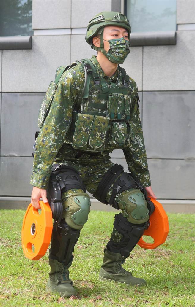 中科院所研制的军用动力外骨骼系统，可强化膝关节，应用在战场上炮弹搬运、重武器操作、伤患救助等任务，现场由中科院工程师示范双手蹲举20公斤的哑铃杠片。（张铠乙摄）