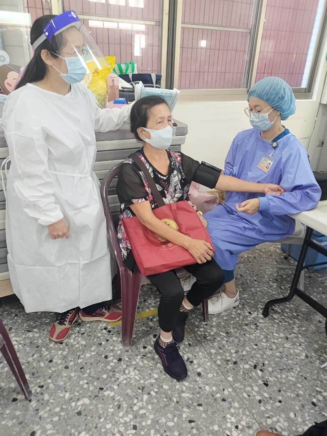 66岁游姓妇人等候接种疫苗，造吊扇砸伤，医护人员关心伤势并量测血压。（读者提供／王文吉台中传真）
