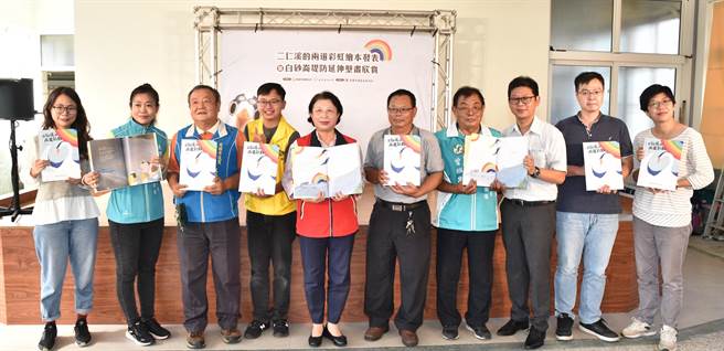 高雄市茄萣舢筏協會27日在茄萣舉行白砂崙堤防彩繪成果發表會，茄萣區長鄭美華（左五）、舢筏協會會長郭寶琳（右五）等人出席，希望透過繪本讓下一代了解當地故事。（林瑞益攝）