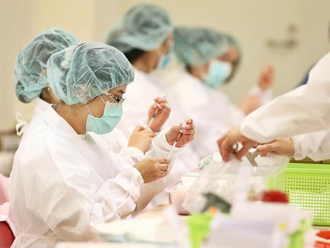 中正纪念堂接种站27日有许多民眾前来施打BNT疫苗，医护人员加紧脚步填充疫苗。（杜宜谙摄）