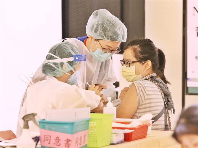 妈妈辛苦背着孩子前来，现场医护人员也帮忙吸引孩子注意力，让妈妈能顺利施打疫苗。（杜宜谙摄）