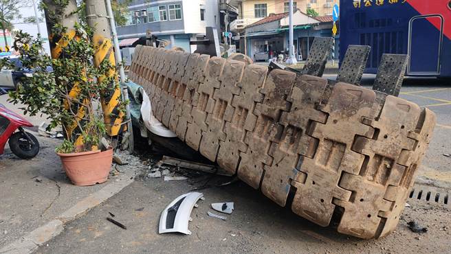 一具10吨重履带突滚落载运的曳引车，路旁停放轿车瞬间压成铁饼。(翻摄自记者爆料网）