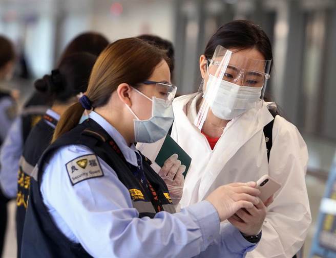 中央流行疫情指挥中心29日公布，国内新增5例新冠肺炎确定病例，均为境外移入，在桃园机场入境管制区内，防疫人员协助旅客上网登录入境健康资料。（范扬光摄）（图中非新闻当事人）
