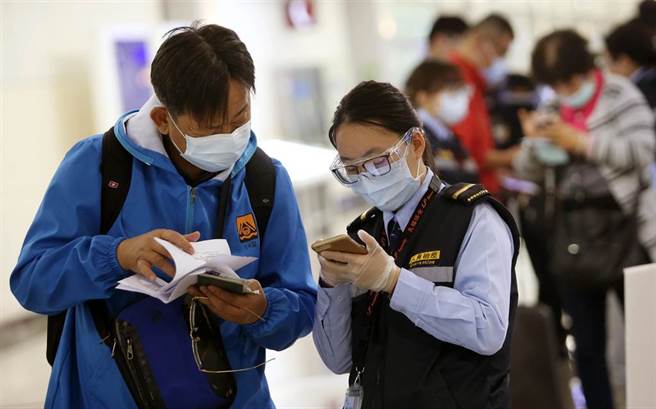 中央流行疫情指挥中心29日公布，国内新增5例新冠肺炎确定病例，均为境外移入，在桃园机场入境管制区内，防疫人员协助旅客上网登录入境健康资料。（范扬光摄）（图中非新闻当事人）
