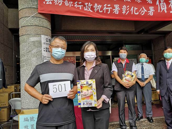 彰化地檢署檢察長俞秀端（右）一早就到場關心扣押的口罩變賣情形，並親自送上紀念品給排隊搶購口罩的民眾。（謝瓊雲攝）