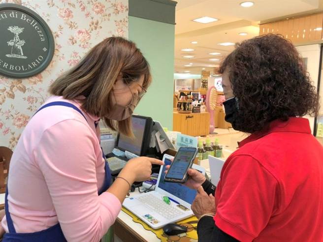 遠百板橋中山有消費者對於使用數位綁定五倍券有疑惑，和專櫃人員一起研究。（遠百提供）