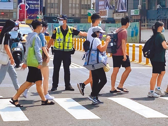 高雄市10月实施交通安全月，图为警方在执法期间在路口保护行人过马路的值勤画面。（高市警局提供／石秀华高雄传真）