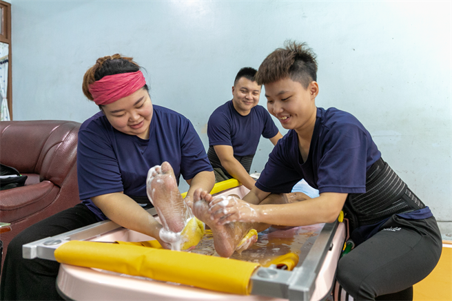 因车祸脑部受伤阿宾，享受到宅沐浴服务后，原本面无表情开始会露出笑容。（永信社会福利基金会提供）