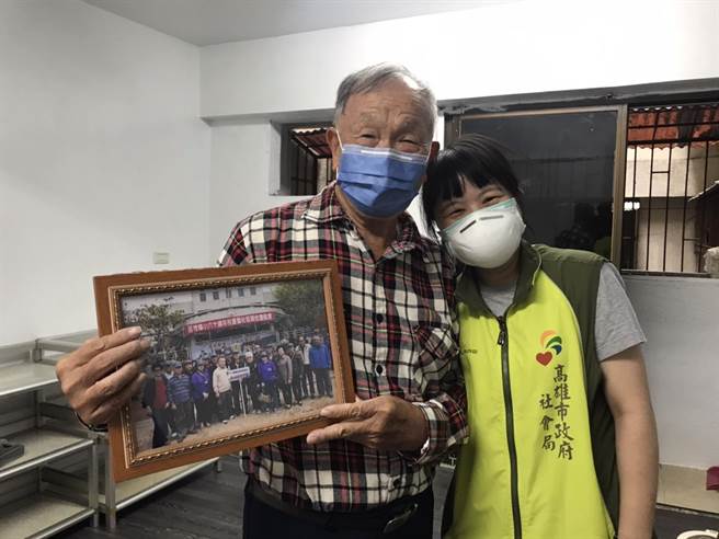 打包過程中，陳伯伯找到他與小學同學60周年及導師的合照，很高興地向社工介紹照片中每位同學。（高雄市社會局提供／林雅惠傳真）