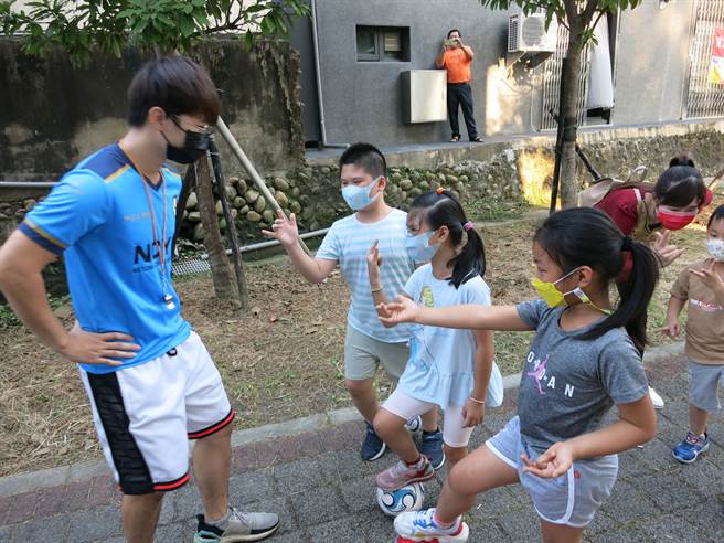 何誠晉香港新二代教導兒童一邊玩一二三木頭人，一邊練習控制足球。(移民署嘉義服務站提供)