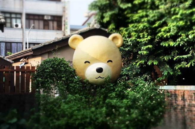 轉角圍牆上的這顆笑臉熊，讓人看了好療癒啊。(圖/行遍天下)