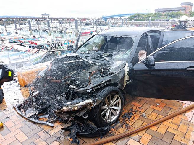 一輛停放在淡水漁人碼頭旁的黑色BMW轎車突然火燒車，整輛車陷入火海嚇壞觀光客。(戴志揚翻攝)
