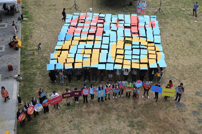 台中市政府經發局13日邀請約200位幸運得主在台中火車站快閃，手拿色板排出藍底及紅、金兩色「台中GO」字樣，將自身好運分享給大家。（陳世宗攝）