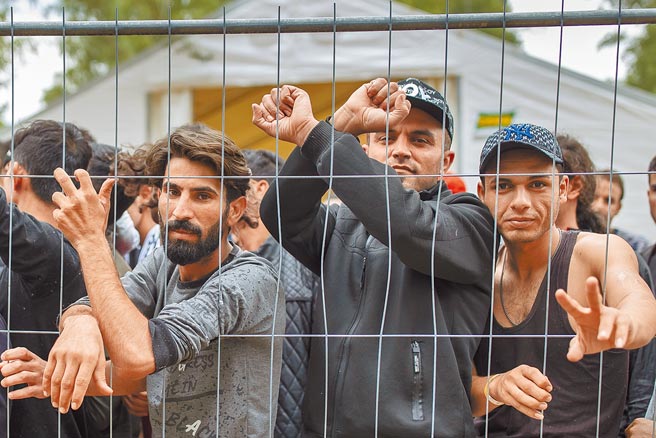 大批来自中东地区的难民，从8月以来陆续涌进波兰与立陶宛等国。图为立陶宛境内一处新建的难民营，大批难民隔着铁丝围篱望向前方，眼神流露无助。（美联社）