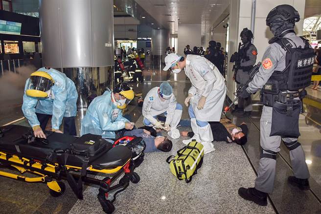 桃機公司15日於第二航廈出境大廳舉辦重大人為危安及恐怖攻擊應變演習，演習相當逼真，現場的爆破場面及槍聲震撼航廈出境大廳。圖為演習模擬暴徒在航廈引爆炸彈造成多人受傷，機場消防救護團隊趕往救護傷患及協助後送。（桃機公司提供）