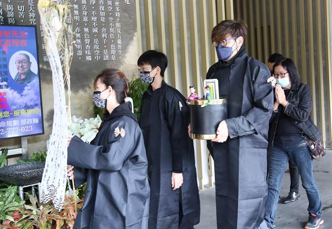 张国栋儿手捧父亲牌位。（陈俊吉摄）