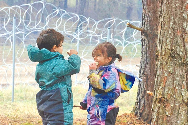 在白羅斯靠近波蘭邊界的一處地點，兩名難民小孩正在享用食物。（美聯社）