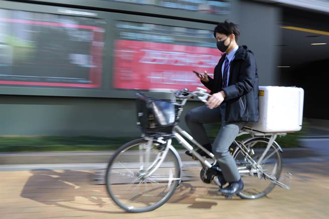 男子骑着单车行经一家证券公司的电子股票板。(图/美联社)  