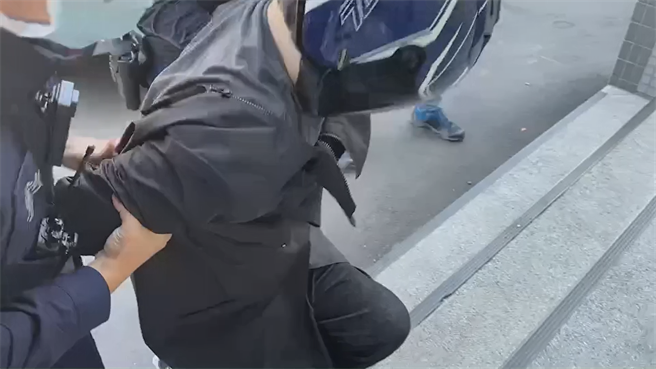 蔣姓男子送往龜山派出所時，上樓梯數度腿軟跪地，還要兩旁員警一路邊扛邊扶才能進入警所。(蔡依珍攝)