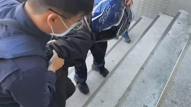 蔣男疑因未戴口罩被制止，竟跑出店外拿刀返回猛死蔡姓店員，遭警方逮捕送往龜山派出所時，上樓梯數度腿軟跪地，還要兩旁員警一路邊扛邊扶才能進入警所。(蔡依珍攝)
