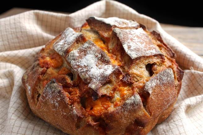 庆祝烘焙将橘色的米摩勒特起司，镶入米契酸麵包中。（庆祝烘焙提供）