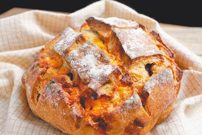 庆祝烘焙将橘色的米摩勒特起司，镶入米契酸麵包中。（庆祝烘焙提供）