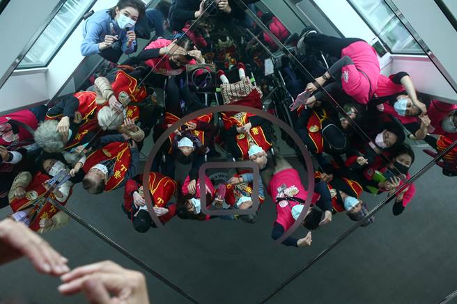 多位长者在感恩节当天受到华山基金会邀请参访101大楼观景台，活动期间大家对着天花板上的镜子合影留念。（邓博仁摄）