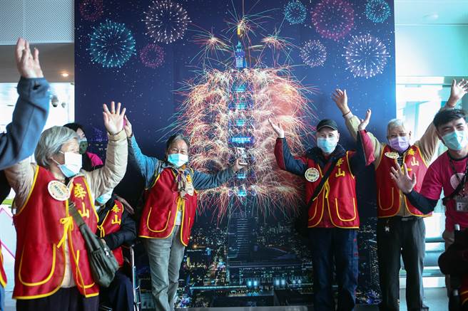 多位长者在感恩节当天受到华山基金会邀请参访101大楼观景台，并在101烟火照片前合影留念。（邓博仁摄）