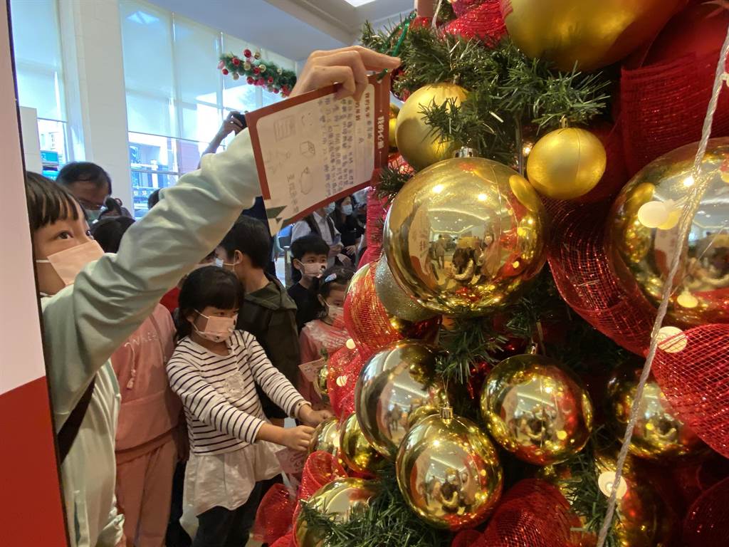 嘉義耐斯王子大飯店「聖誕心願卡」活動今天起跑，孩子將心願卡掛到耶誕樹上。（廖素慧攝）