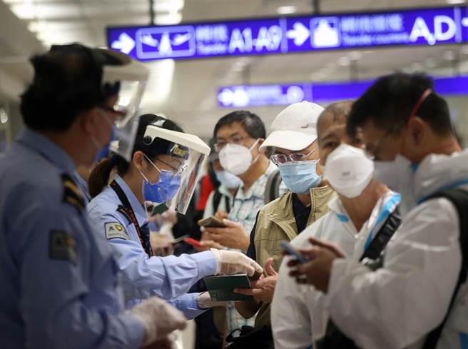 中央流行疫情指挥中心公告自11月29日0时（航机抵台时间）起，将南非、波札那、纳米比亚、赖索托、史瓦帝尼及辛巴威等6国列为「重点高风险国家」，在桃园机场入境管制区内，防疫人员协助旅客上网登录入境健康资料。（范扬光摄）