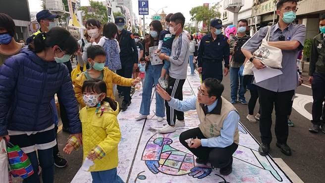 台南市長黃偉哲走在藝術節彩繪馬路上，沿路發送糖果給民眾。（程炳璋攝）