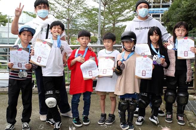 滑板競速障礙賽項目，參賽的國小組選手分成低、中、高年級組參與比賽，得獎的一群小朋友高興的跟帶領他們的教練合影，展示豐厚的成果。（鄭任南攝）