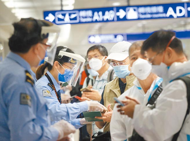 中央流行疫情指挥中心公告将南非、波札那、纳米比亚、赖索托、史瓦帝尼及辛巴威等6国列为「重点高风险国家」，在桃园机场入境管制区内，防疫人员协助旅客上网登录入境健康资料。（范扬光摄）